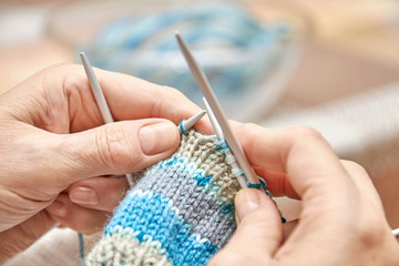 Woman knits socks. A hobby of elderly woman is knitting. Closeup view of knitting loop. Selective focus