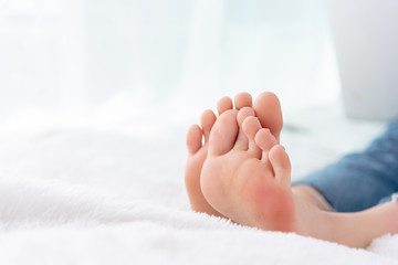 Closeup woman feet skin wearing jeans on white bed. Healthcare and health medical concept.