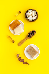 Cosmetics for hair care with argan and jojoba oil on yellow background top-down