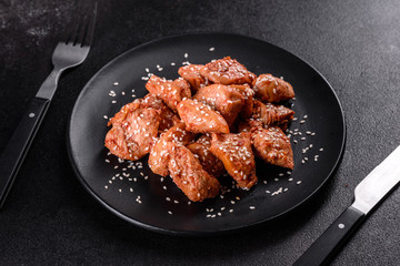 Chicken fillet in sesame seeds, teriyaki sauce on a black stone plate
