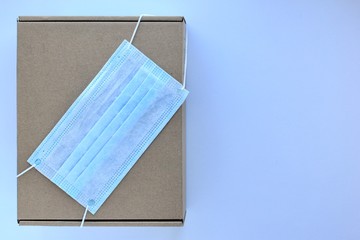 Brown post box with medical mask on it. Medicine concept of biohazard of postal parcels, seasonal diseases. Copy space, top view.