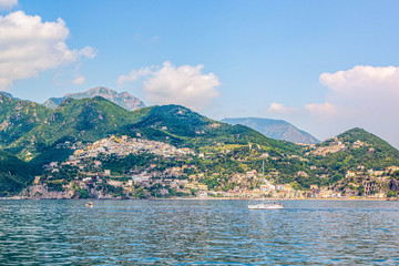 Fototapeta premium Panoramic view of small haven of Amalfi village with turquoise sea and colorful houses on slopes of Amalfi Coast with Gulf of Salerno, Campania, Italy.