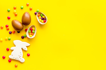 Easter sweets frame. Chocolate eggs and bunny gingerbread on yellow background top-down frame copy space