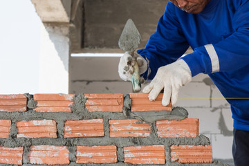 Worker installing brick for wall in construction,selective focus.