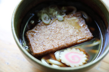 kitsune udon noodles with fish ball and tofu on wood background japanese food