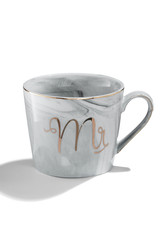 Subject shot of a ceramic cup with gray marble pattern, gold trimmings and letters 