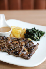 beef steak with potato on wood background
