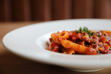Penne arrabiata pasta tomato sauce with spices italian food on wood background