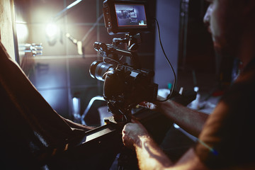 Video production backstage. Behind the scenes of creating video content, a professional team of cameramen with a director filming commercial ads. Video content creation, video creation industry. Low