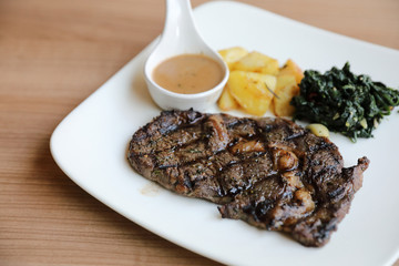 beef steak with potato on wood background