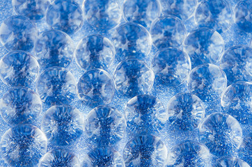 Naklejka premium Abstract blue background with transparent glass balls on glitter backdrop, texture, pattern.