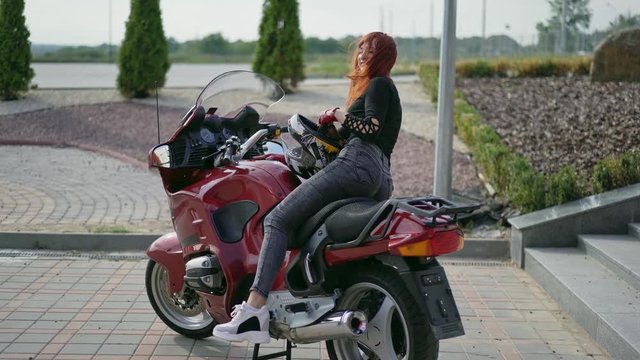 Girl sitting on motorcycle. Beautiful biker girl sitting on superbike outside