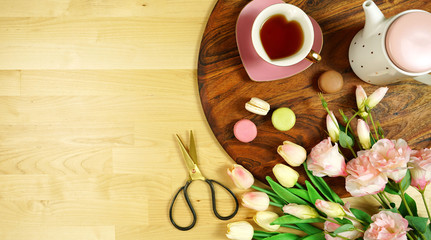 Hello Spring theme creative layout concept flat lay tea break with pink tulips and lisianthus flowers, sun hat on wooden table background, with negative copy space.