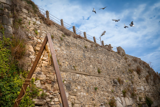 The gallows near stone wall and and blurred birds in sky. Concept of death, hope and freedom.