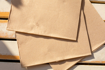 A recycled paper napkins lies on the cafe's light wooden table in the morning sun.