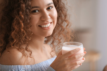 Young woman drinking tasty yogurt in kitchen