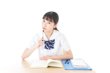 机で勉強をする制服姿の女子学生