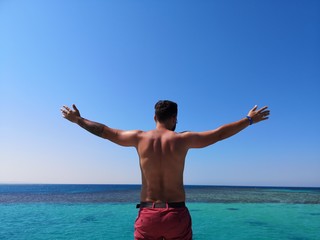  men's back against the backdrop of a water plexus of the sea, relax and high on the sea