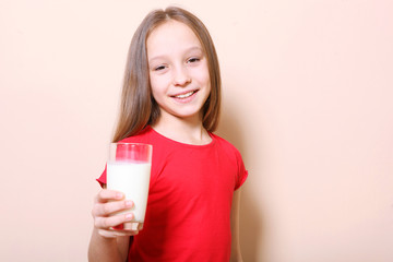 Child with glass of milk on a colored background.