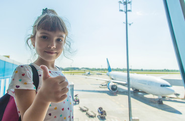 A child at the airport on the background of the aircraft. Selective focus.