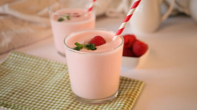 Woman hand put on the table glass of natural homemade yogurt with fresh raspberry. Breakfast concept