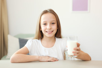 Child with glass of milk on a light background.