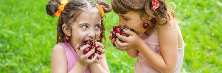 Children eat cherries in the summer. Selective focus.