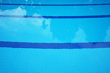 Close up swimming pool row lanes with light and dark blue square floor tiles underneath