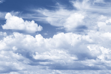 sunny cloudscape blue sky with white cumulus clouds, tinted in classic blue. background backdrop sky. Weather idyllic cloudy sky