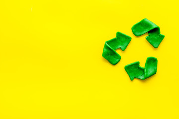 Recycling symbol - green arrows - on yellow background top-down copy space