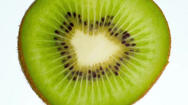 4k video of slice of kiwi fruit squeezing and exploding on white background. Perfect abstract backdrop for organic food and healthy nutrition.