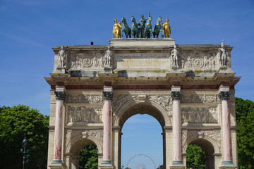 Fototapeta na wymiar old stone monument with an arch, horses statues and the ferris wheel in the back in Paris, France