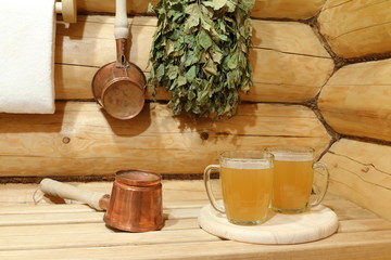 Two glass mugs of light beer in the interior of sauna among copper accessories. 