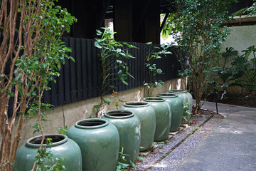 Fototapeta na wymiar Thai style glazed earthenware water jars decorated in green plant garden park
