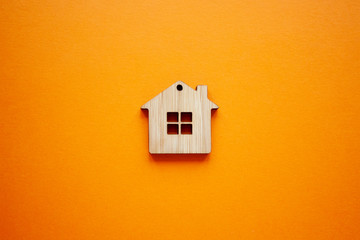 House, insurance and mortgage, buing and rent concept. Small wooden house toy on orange background...