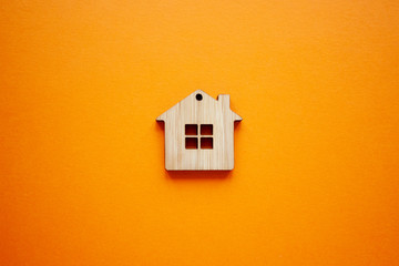 House, insurance and mortgage, buing and rent concept. Small wooden house toy on orange background top view