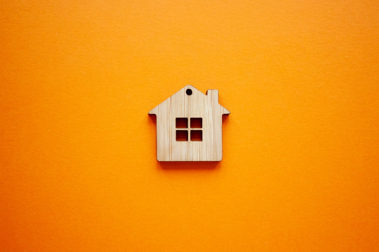 House, insurance and mortgage, buing and rent concept. Small wooden house toy on orange background top view