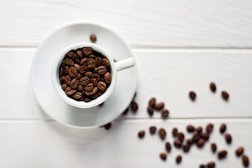 Cup of aromatic coffee in beans on a white wooden background. Flat lay.