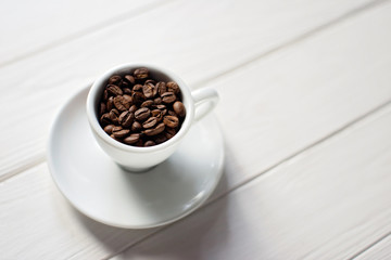 Cup of aromatic coffee in beans on a white wooden background. Flat lay. Copy space for text.