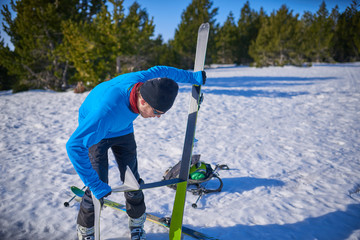 Person sticking climbing skins on splitboard on the snow.