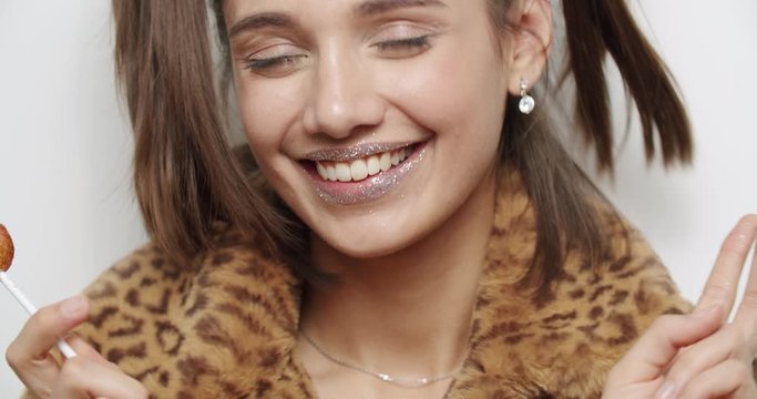 female model wearing leopard fur coat licking candy