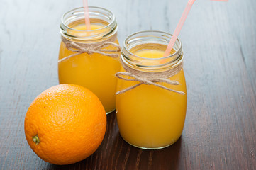 Fototapeta na wymiar Orange juice and whole orange in two jars rustic style side view, copy space