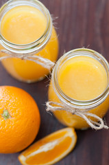 Orange, slice and juice in jars on a dark wooden table, rustic style top view, copy space, vertical format