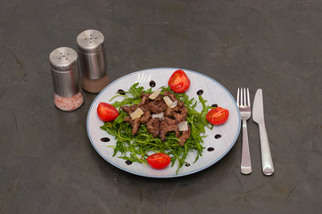 Tasty and juicy grilled meat arugula, cheese, tomato sauce and spices on a dark gray concrete background, top view