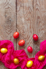 Colorful Easter eggs and silk textile material on the wooden background. Festive Easter holiday concept. View from above. Copy space. Top view