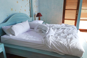 Bedroom with white pillow on the blue bed which rest,interior and comfort unmade bed in the morning
