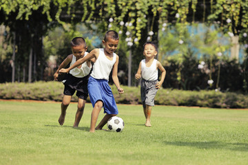 Asian boys playing football on the lawn with fun..