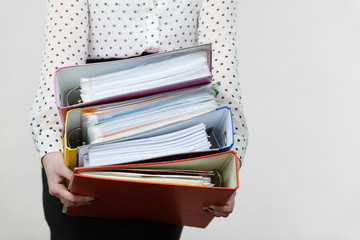 Woman holding heavy colorful binders with documents
