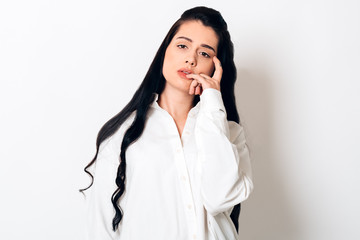 sensual young woman with long black hair looking at camera on white background