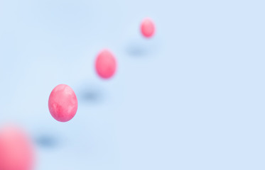 Four flying pink chiken eggs on a blue background. Place for your text